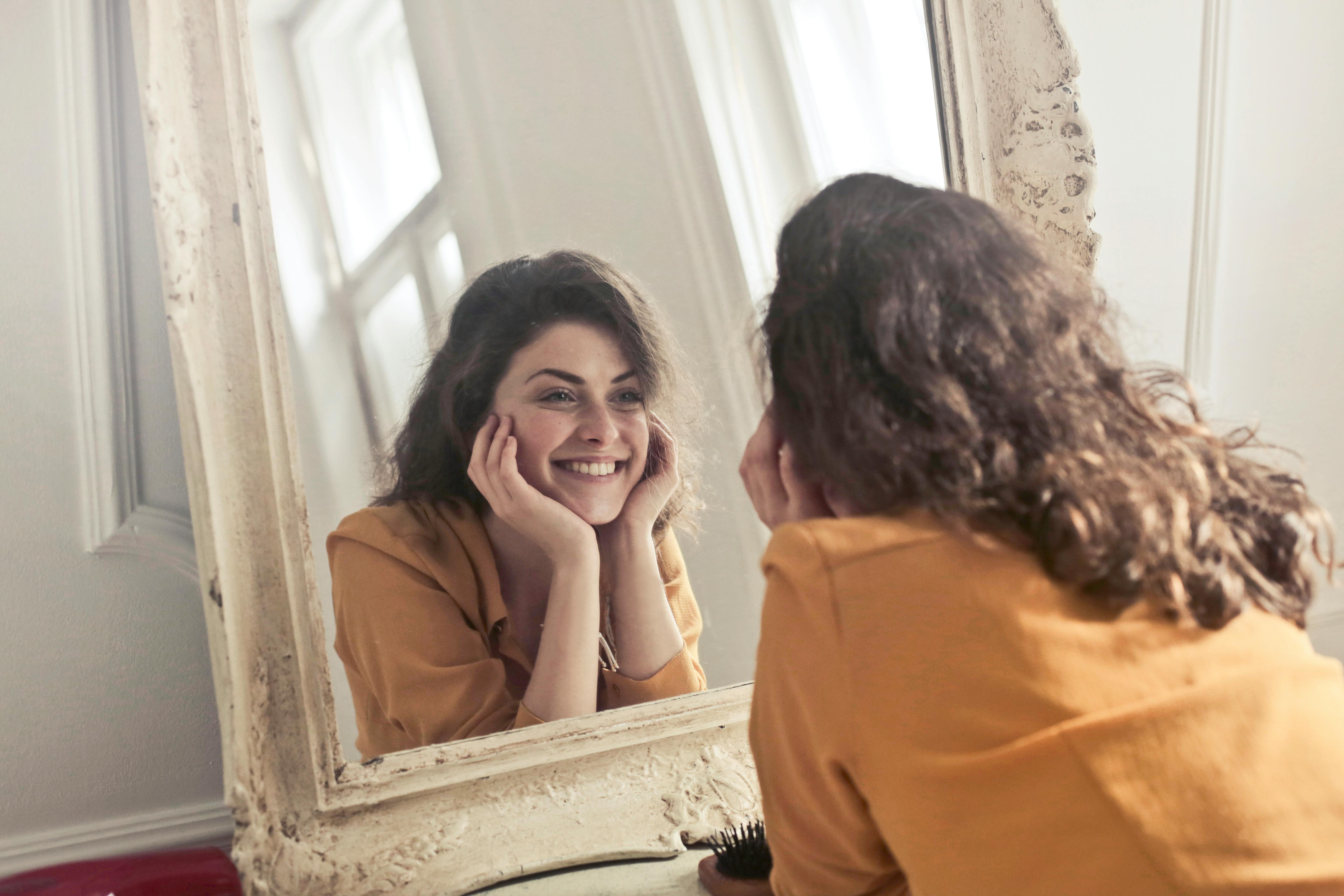 A happy woman looking into the mirror | Source: Pexels